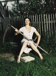 Woman sitting in garden, holding scythe - 00013DK