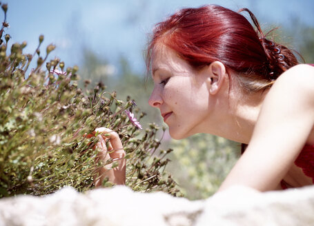 Frau riecht an Blumen, im Freien - 00116PE