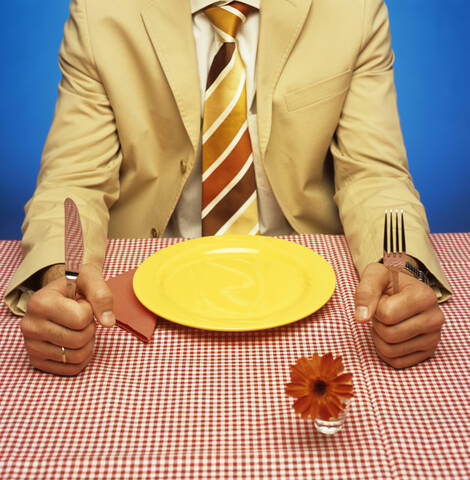 Mann sitzt am Tisch mit leerem Teller, lizenzfreies Stockfoto