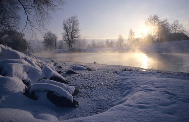 Deutschland, Bayern, Loisach, Sonne spiegelt sich in Fluss und schneebedeckten Felsen in der Morgendämmerung - EK00333