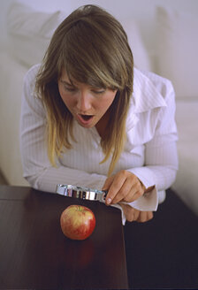 Woman looking at apple through magnifying glass - DK00049