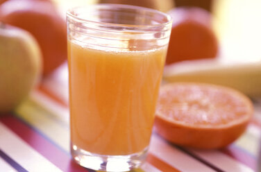 Glas mit frischem Orangensaft und Früchten im Hintergrund - 00350AS