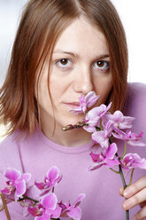 Young woman smelling orchid, portrait, close up - LDF00060