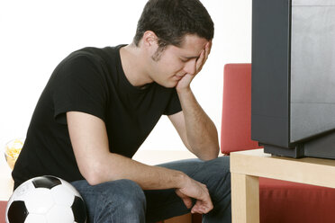 Disappointed young football fan holding head in hand - LDF00054