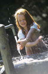 Mädchen spielt mit dem Wasser eines Springbrunnens - HHF00062