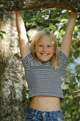 Girl (10-12) climbing on tree, smiling - 00462CR