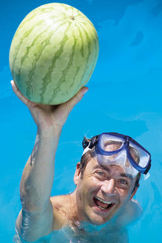 Man in swimming pool playing with water melone stock photo