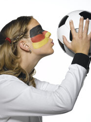 Frau mit deutscher Flagge im Gesicht und in deutscher Fußballkleidung küsst einen Fußball, Nahaufnahme - LMF00012