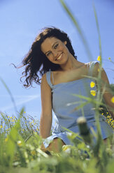 Woman laughing sitting in meadow - LDF00098
