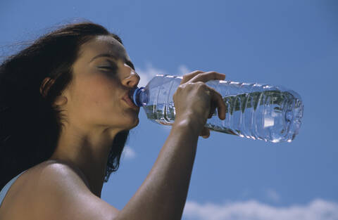 Frau trinkt Wasser aus einer Flasche, lizenzfreies Stockfoto