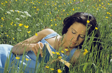 Woman reading book and lying in meadow - LDF00085