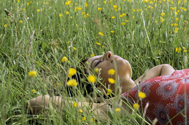 Junge Frau im Gras liegend mit Händen hinter dem Kopf - LDF00079