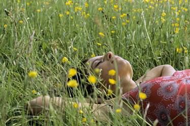 Young woman lying on grass with hands behind head - LDF00079