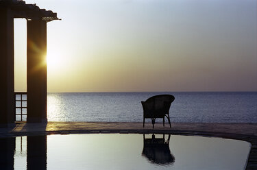 Chair by beach swimming pool at sunset - UKF00061