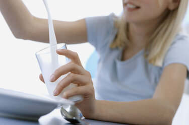 Girl pouring milk into a glass - ASF01360