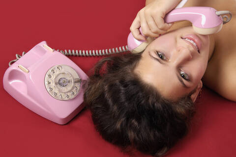Junge Frau hält Telefonhörer, lizenzfreies Stockfoto