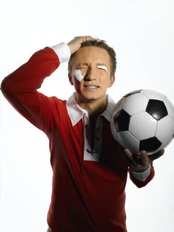 Junger Mann mit polnischer Flagge im Gesicht, der einen Fußball hält, Augen geschlossen, lizenzfreies Stockfoto