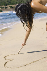 Woman drawing heart into sand - LDF00128