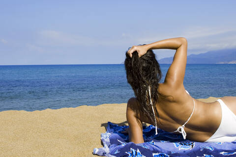 Frau am Strand liegend, Rückansicht, lizenzfreies Stockfoto