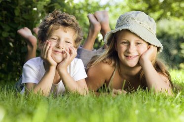 Junge und Mädchen (6-9) im Gras liegend, Porträt - CKF00107