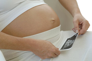 Expectant mother looking at sonogram of baby, midsection - CRF00727