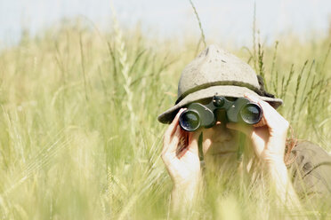 Young woman using binoculars in wheat field - CLF00050