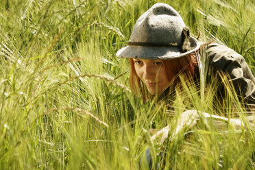 Junge Frau versteckt sich in einem Feld und schaut weg, Nahaufnahme - CLF00047