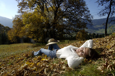 Junge Frau auf Herbstblättern liegend, Porträt - HHF00140