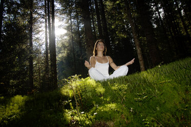 Young woman mediating in forest, low angle view - HHF00135