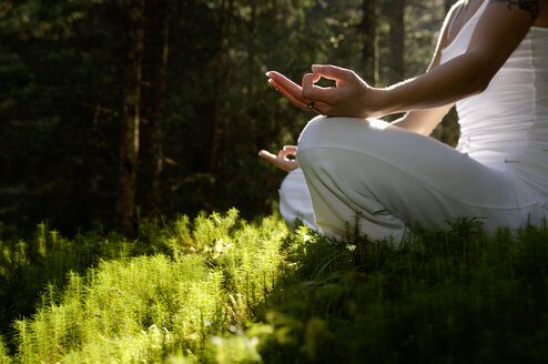 Woman sitting in meditating position outdoors, low angle view - HHF00134