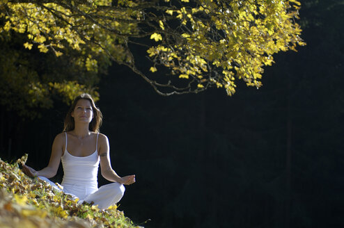 Young woman mediating in forest - HHF00128
