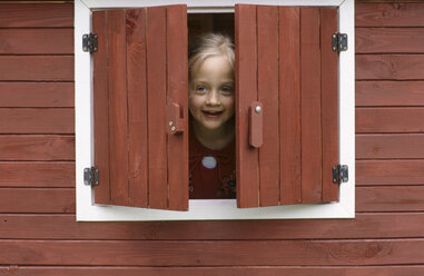 Girl (6-7) looking through window, smiling - CRF00742