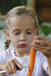 Girl (6-7) peeling carrot, close-up - CRF00787