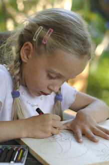 Mädchen (6-7) zeichnet mit Buntstiften am Tisch - CRF00785