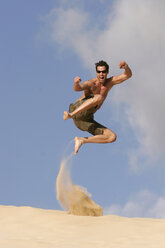 Man jumping off sand dune - RDF00092