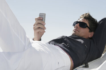 Mann schaut auf ein Mobiltelefon, niedriger Blickwinkel - RDF00086