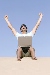 Man sitting on sand with laptop - RDF00046