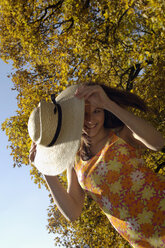 Young woman holding hat, smiling, portrait - HHF00181