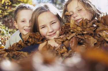 Children (4-13) lying on autumn leaves - WEPF00291