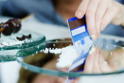 Woman cutting sweets on mirror with credit card, close-up stock photo