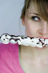 Junge Frau isst Schokoladenbonbon und schaut zur Seite - MFF00124