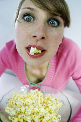 Junge Frau isst Popcorn, Porträt, Blick von oben, lizenzfreies Stockfoto
