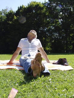 Mann sitzt auf einer Decke im Park - DKF00092