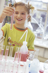 Girl (8-9) holding test tube in chemical lab, smiling - WESTF00015