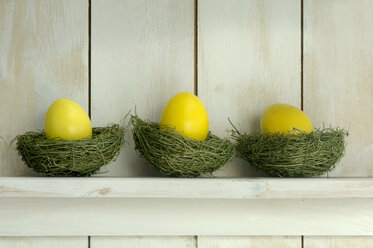 Yellow Easter eggs lying on shelf on grass - ASF01826