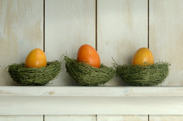 Orangefarbene Ostereier liegen im Nest auf dem Regal - ASF01824