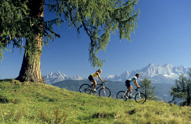 Austria, Salzburger Land, couple mountain biking, side view - HHF00244