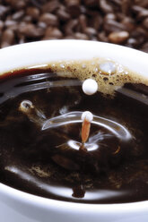 Tasse Kaffee auf Kaffeebohnen, Nahaufnahme - 03121CS-U