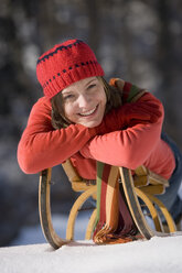 Young woman lying on sledge, portrait, smiling - WESTF00165