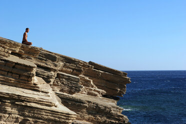 Greece, Crete, man exercising yoga on cliff - MIEF00004